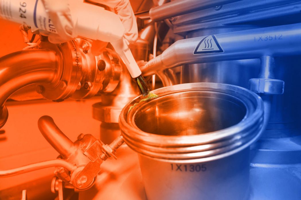 Mit einer ELKALUB Pinseldose wird Schmierstoff auf die Gummidichtung eines offenen Verbindungsstücks von einem großen Rohr aufgetragen. Im Hintergrund sind Rohre und Ventile abgebildet.