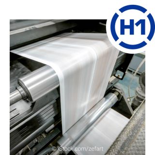 View of a running roll-fed printing press. The freshly printed paper is transported over several rolls. The H1 logo is shown at the top right.