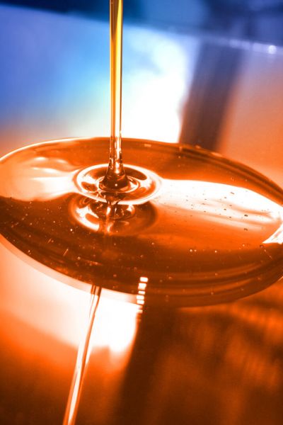 Lubricating oil is poured from above onto a reflective surface and spreads out in a circle.