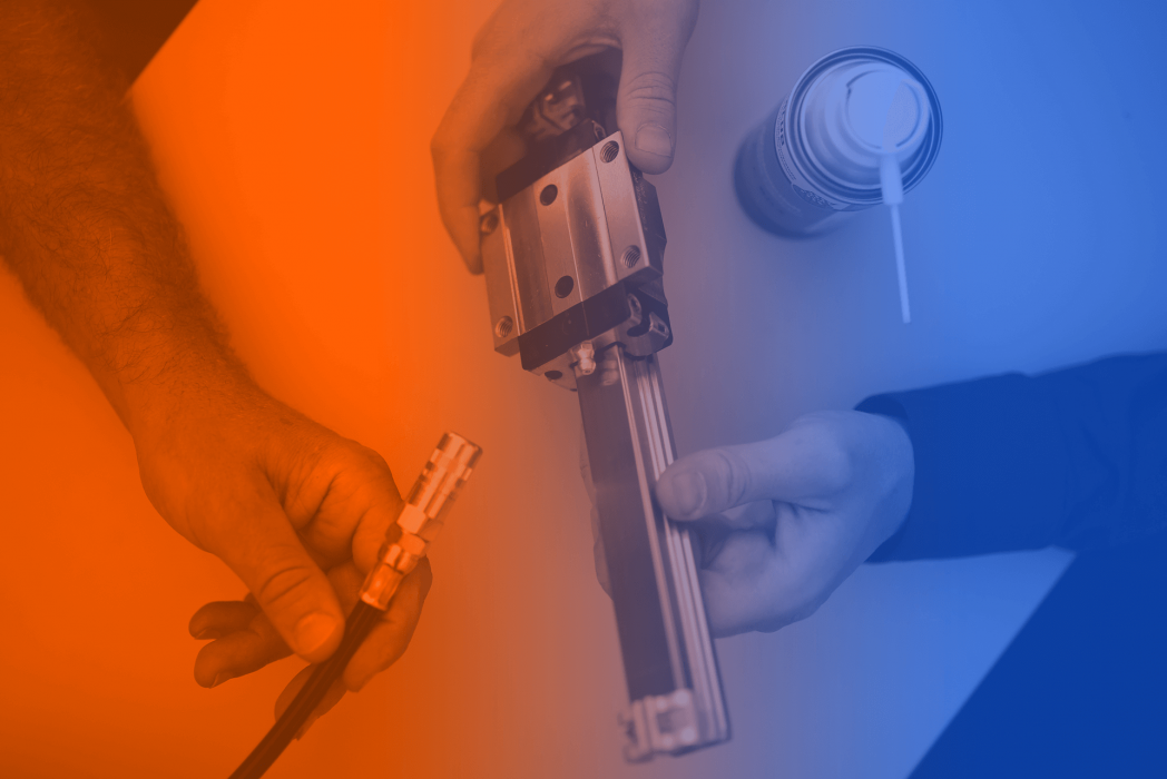 Blick auf die Hände zweier ELKALUB Entwickler beim Test eines Schmiermittels für Linearführungen. Einer hält eine Linearführung, der andere das Schlauchstück eines Schmiermittelgebers. Daneben steht eine Spraydose eines ELKALUB Spezialschmierstoffs.