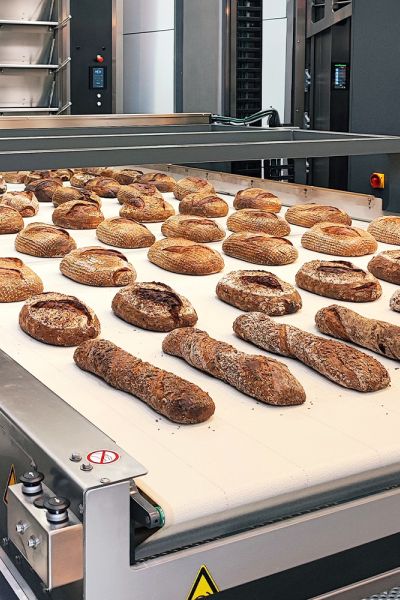 Darstellung eines mit ELKALUB H1-Hochtemperturschmiermitteln behandelten Förderbands mit Brotrohlingen