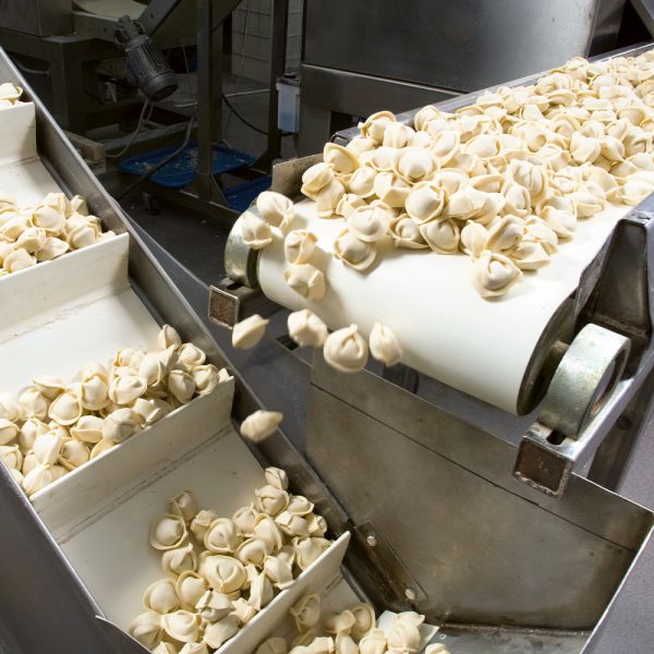 Darstellung eines Förderbands, das Teigwaren auf eine Verpackungsmaschine leitet. Die Maschinen sind mit ELKALUB H1-Schmierstoffen behandelt.