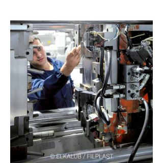 Image of a plastics processing machine being treated with ELKALUB lubricants by an employee.