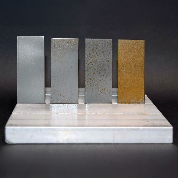 Darstellung eines Korrosionstets. Vier Metallstreifen: Links mit ELKALUB Korrosionsschutzmitteln behandelt, rechts ohne.