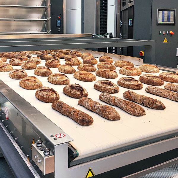 Darstellung eines mit ELKALUB H1-Hochtemperturschmiermitteln behandelten Förderbands mit Brotrohlingen