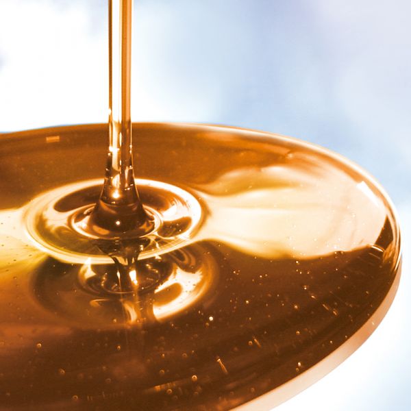 Darstellung eines Spezial-Schmieröls von ELKALUB das auf eine Fläche gegossen wird