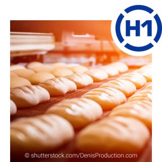 Bread blanks lie in a row on the conveyor belt of a production oven in the bakery.