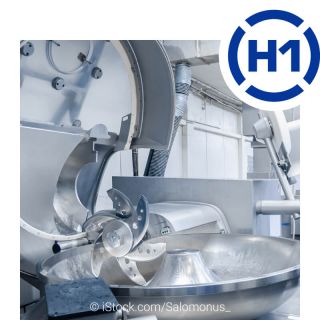 View into a meat processing factory for the production of sausages and meat products. In front is an industrial cutter for grinding meat.