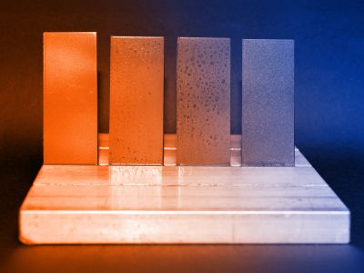 Darstellung eines Korrosionstets. Vier Metallstreifen: Links mit ELKALUB Korrosionsschutzmitteln behandelt, rechts ohne.