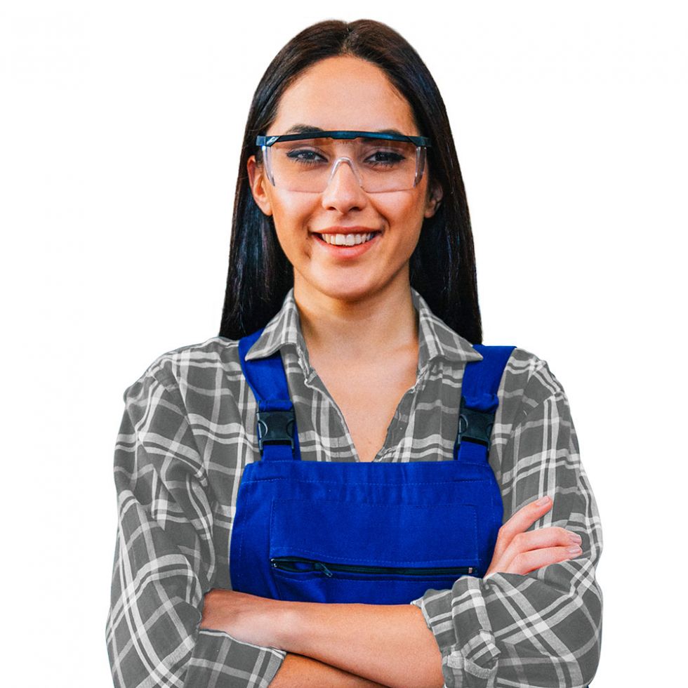 Abbildung einer jungen Frau in Blaumann mit Schutzbrille. Sie lächelt freundlich und hat die Arme verschränkt.